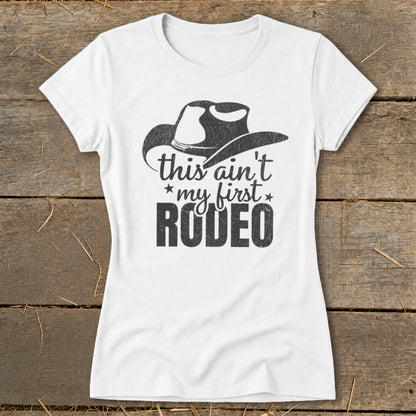 White t-shirt with a cowboy hat graphic and text "this ain't my first RODEO".
