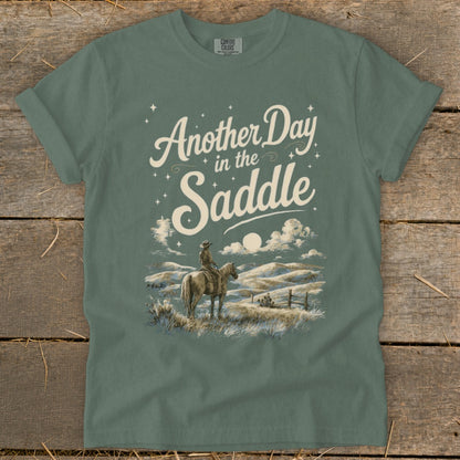 Green t-shirt with "Another Day in the Saddle" text and rider on horseback.