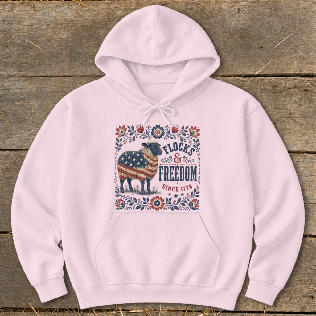 Pink hoodie with sheep design featuring American flag and text "Flocks & Freedom Since 1776".