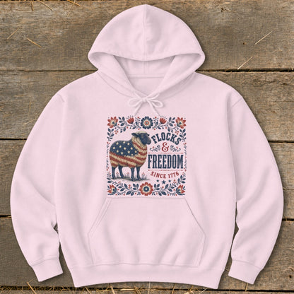 Pink hoodie with sheep design featuring American flag and text "Flocks & Freedom Since 1776".