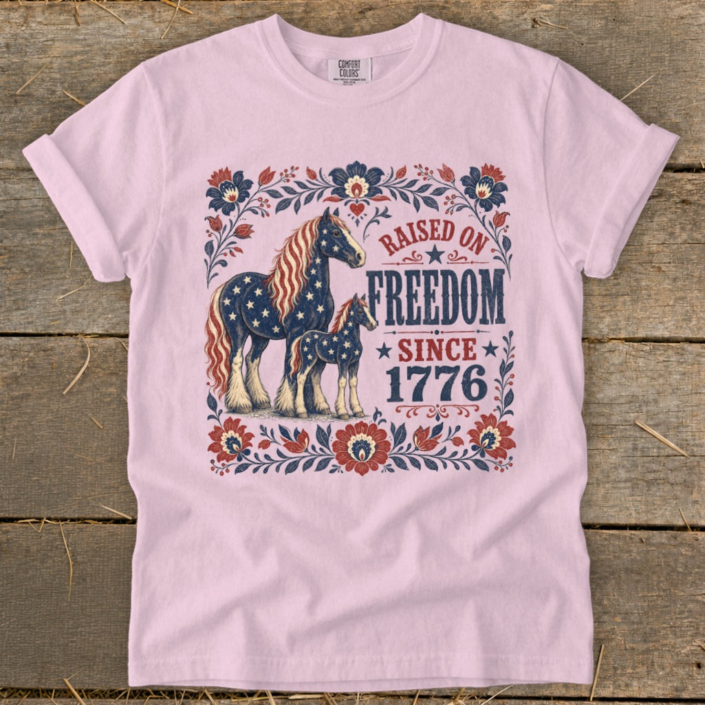 Pink t-shirt with horses and patriotic text "Raised on Freedom Since 1776".