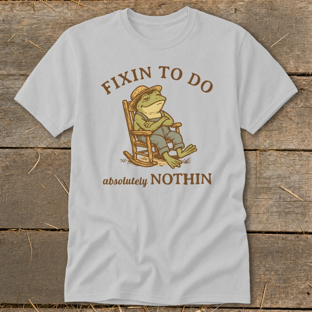 Frog in rocking chair with arms crossed, text reads "Fixin to do absolutely nothin".
