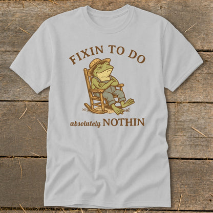 Frog in rocking chair with arms crossed, text reads "Fixin to do absolutely nothin".
