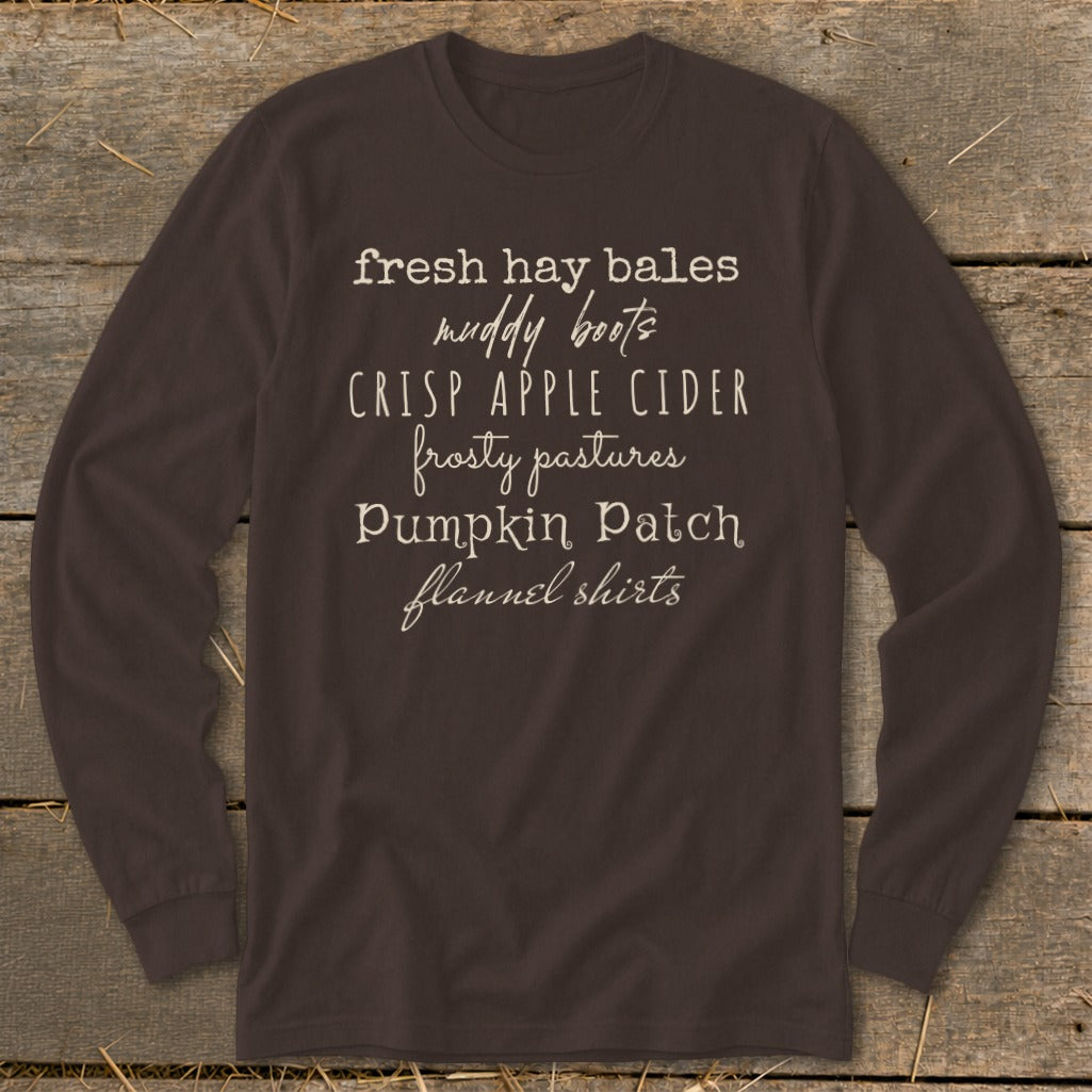 Brown long-sleeve shirt with text listing fall activities: fresh hay bales, muddy boots, crisp apple cider.