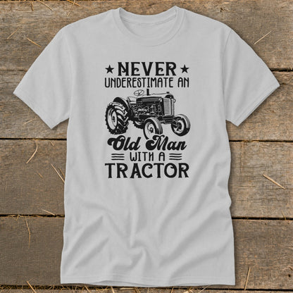Light gray t-shirt with black text and tractor graphic. Never underestimate an old man with a tractor.