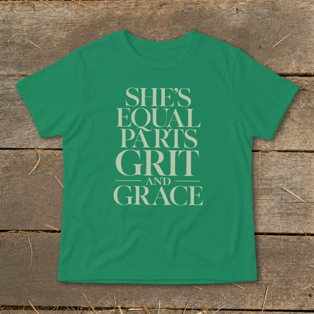 Green t-shirt with cream text reading "She's Equal Parts Grit And Grace".
