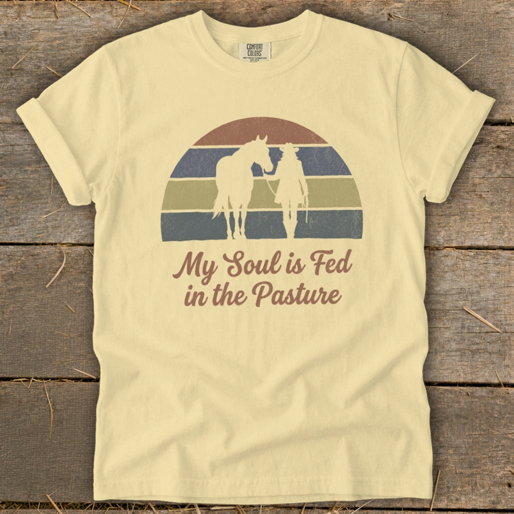 Light yellow t-shirt with retro sunset graphic and text "My Soul is Fed in the Pasture".