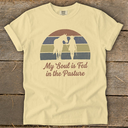 Light yellow t-shirt with retro sunset graphic and text "My Soul is Fed in the Pasture".