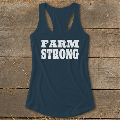 Dark blue racerback tank top with the distressed white text "FARM STRONG" on a wooden background.