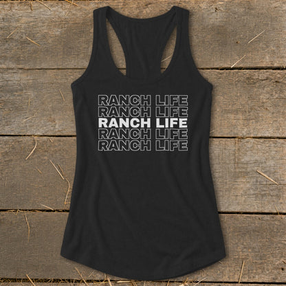 A black racerback tank top with repeated white text reading Ranch Life laid flat on wooden boards.