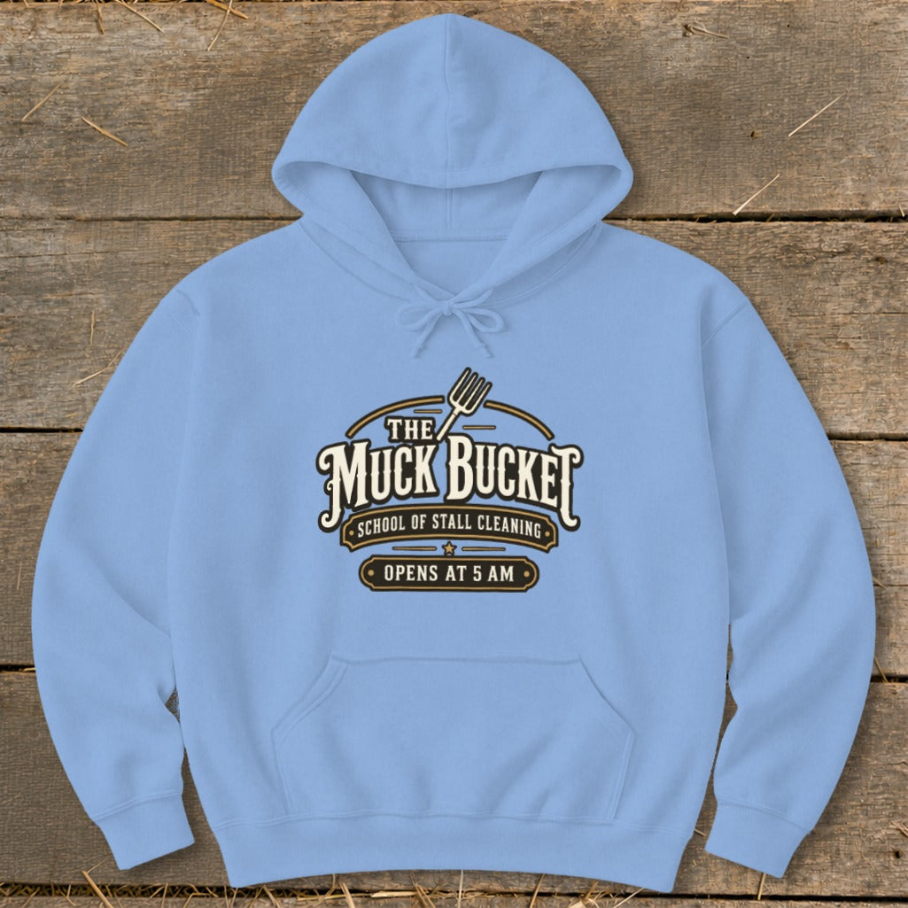 Light blue hoodie with "The Muck Bucket School of Stall Cleaning Opens at 5 AM" logo.