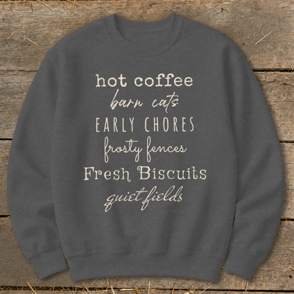Dark gray sweatshirt with text: hot coffee, barn cats, EARLY CHORES, frosty fences, Fresh Biscuits, quiet fields.