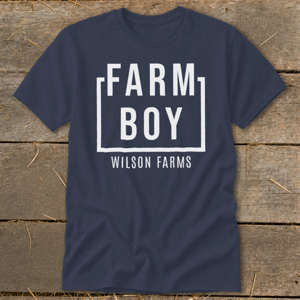 Navy blue t-shirt with white text "Farm Boy Wilson Farms" inside a box.