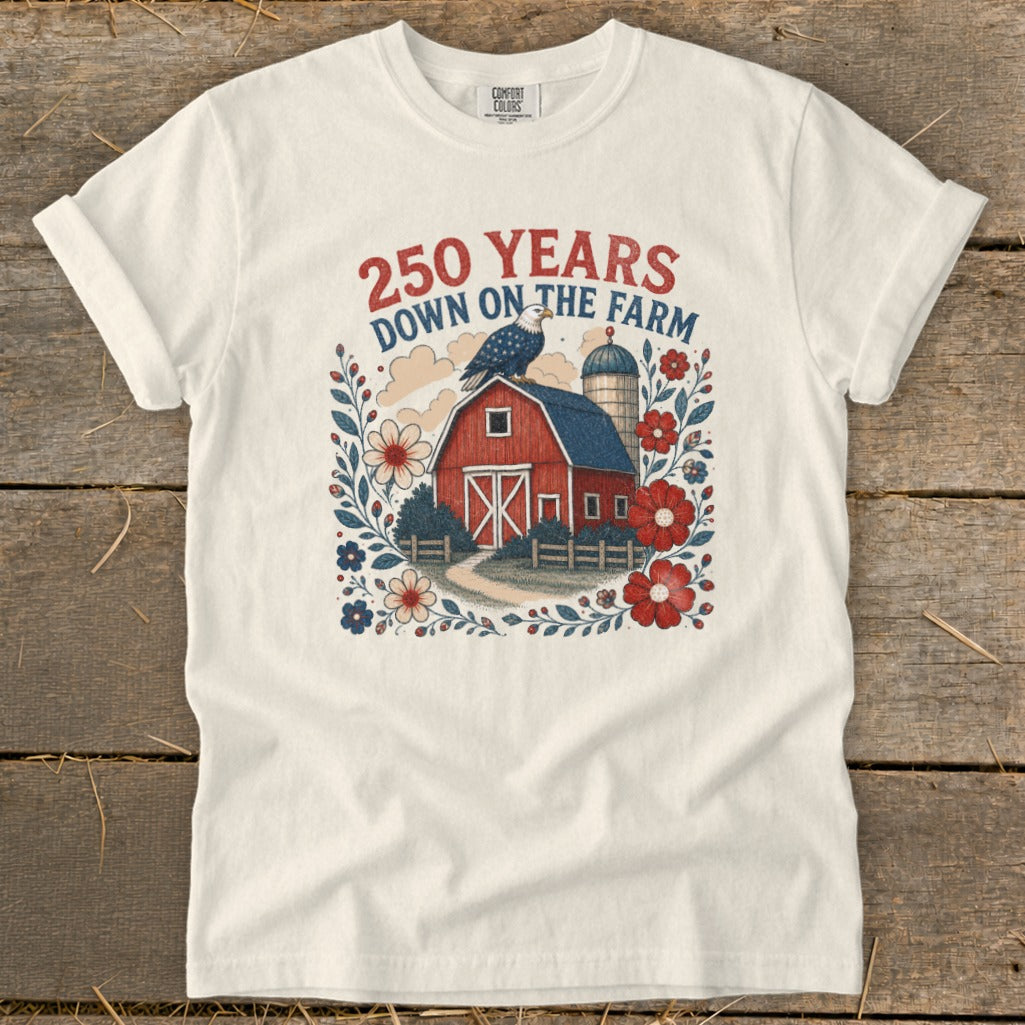 Cream t-shirt with graphic of red barn, silo, eagle, and floral border.