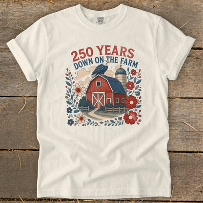 Cream t-shirt with graphic of red barn, silo, eagle, and floral border.