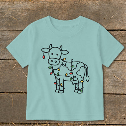 Light blue t-shirt with a black outline drawing of a cow decorated with Christmas lights.