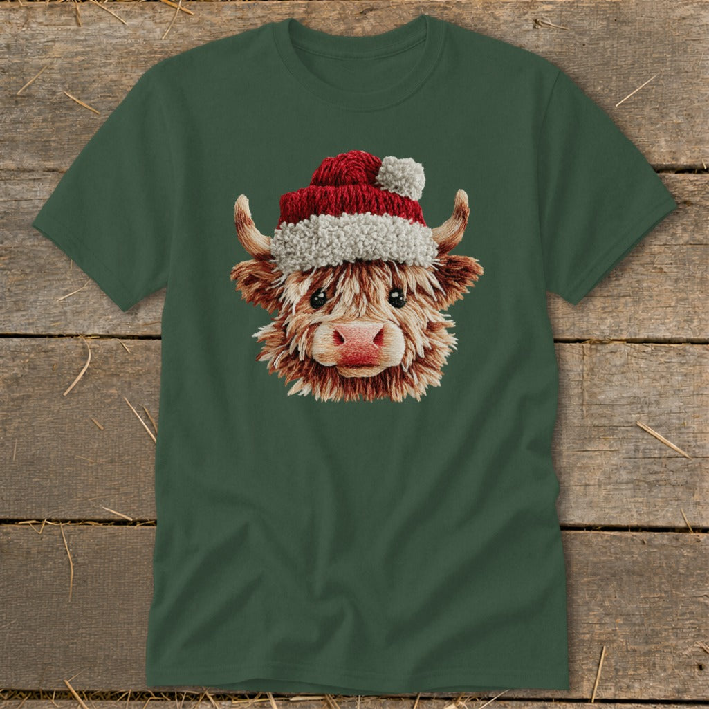 Highland cow wearing a Santa hat graphic on a green t-shirt.