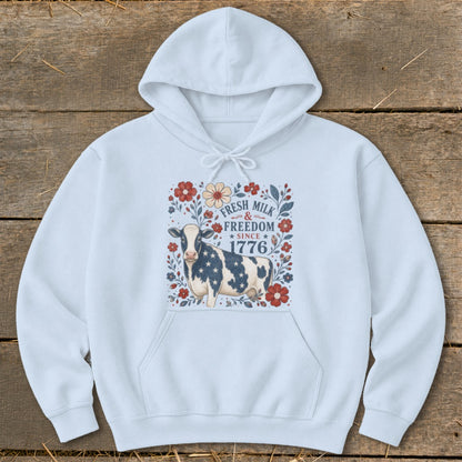 Light blue hoodie with a cow and floral graphic that says "Fresh Milk & Freedom Since 1776".