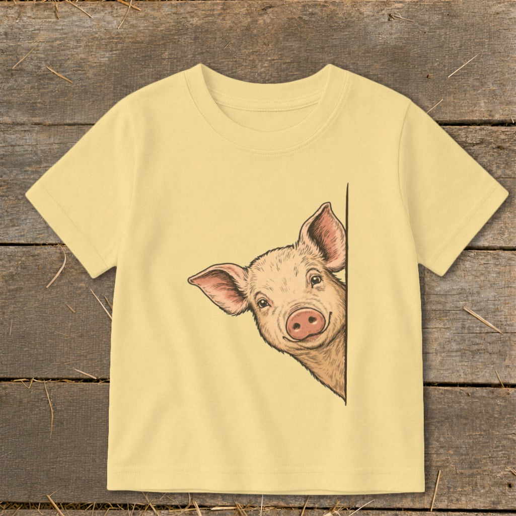 Light yellow t-shirt with a drawing of a peeking pig's head on the left side.