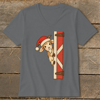 Goat wearing a Santa hat peeking around a red barn door on a gray t-shirt.