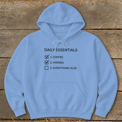 Light blue hoodie with "Daily Essentials" checklist: coffee, horses, everything else.