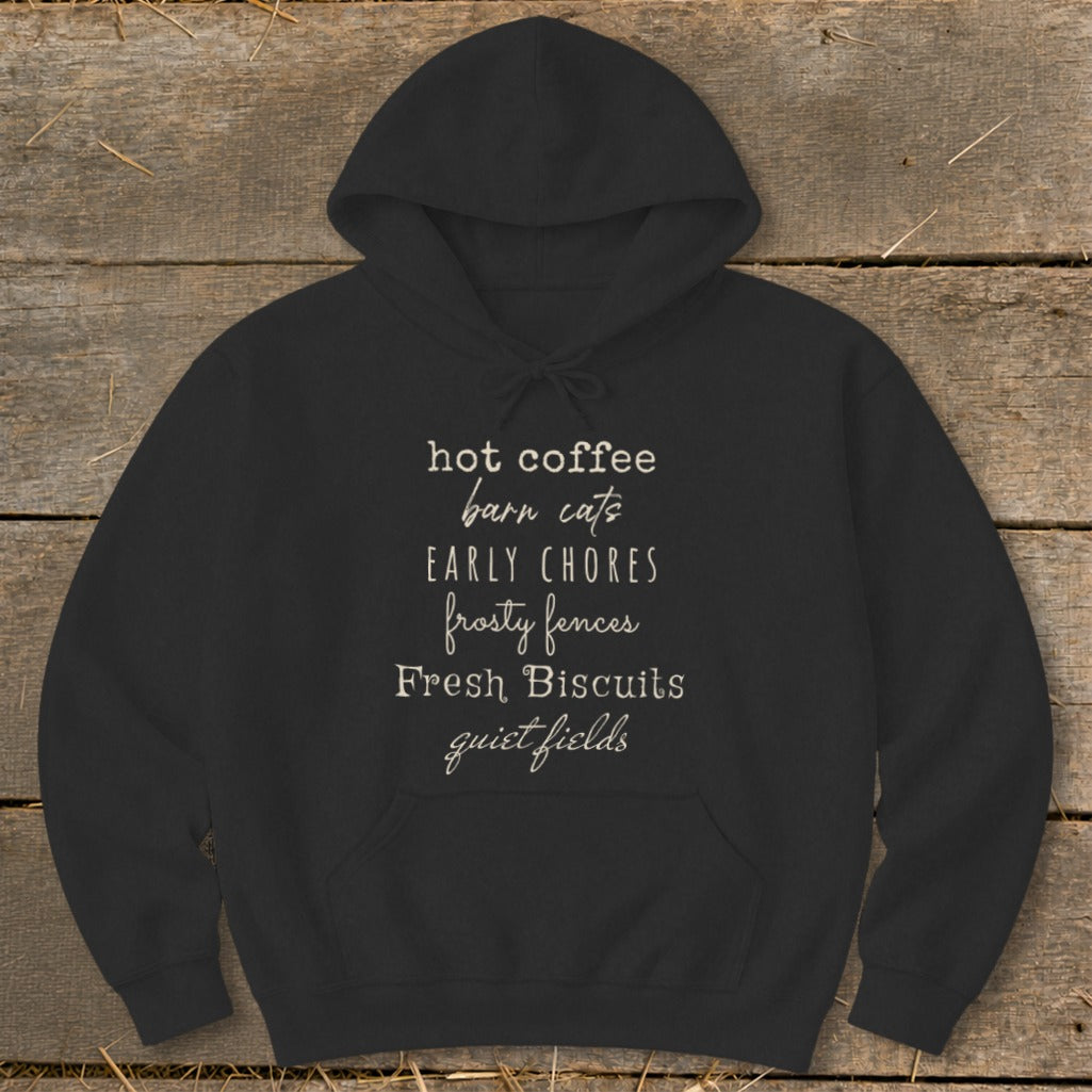 Black hoodie with white text listing: hot coffee, barn cats, early chores, frosty fences, fresh biscuits, quiet fields.