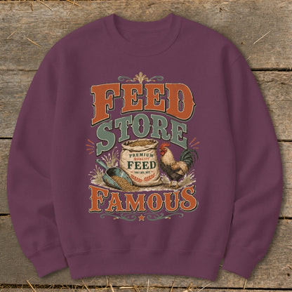 Feed Store Famous graphic with rooster, feed bag, and scoop on purple sweatshirt.