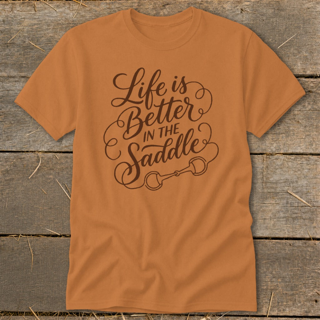 Orange t-shirt with brown text "Life is Better In The Saddle" and horse bit graphic.