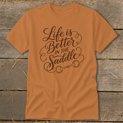 Orange t-shirt with brown text "Life is Better In The Saddle" and horse bit graphic.