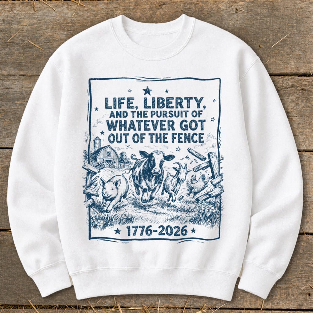 White sweatshirt with "LIFE, LIBERTY, AND THE PURSUIT OF WHATEVER GOT OUT OF THE FENCE 1776-2026" text and farm animals.