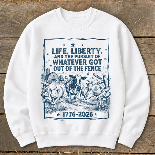 White sweatshirt with "LIFE, LIBERTY, AND THE PURSUIT OF WHATEVER GOT OUT OF THE FENCE 1776-2026" text and farm animals.