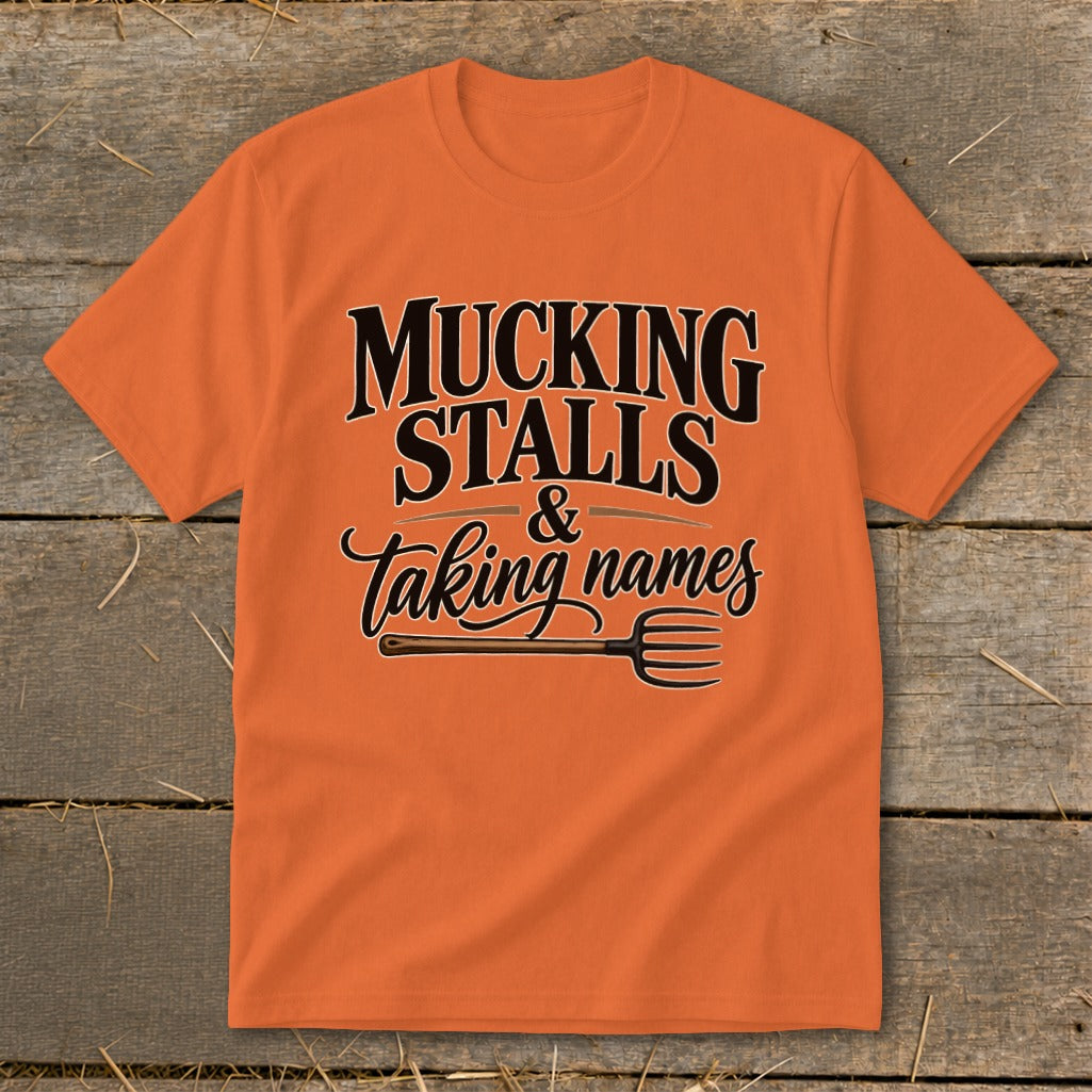 Orange t-shirt with "Mucking Stalls & Taking Names" text and a pitchfork graphic.