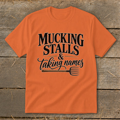 Orange t-shirt with "Mucking Stalls & Taking Names" text and a pitchfork graphic.