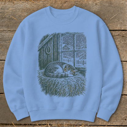Light blue sweatshirt with a cat sleeping on hay by a snowy barn window.