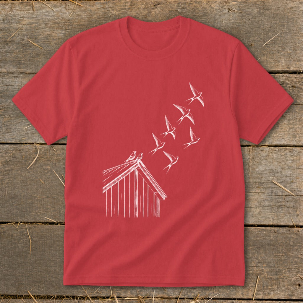 A red crewneck t-shirt featuring a white line drawing of birds flying from a small wooden building.