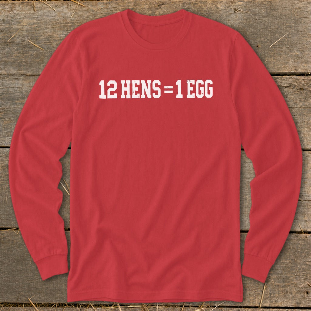 A red long-sleeve t-shirt with white block text reading 12 HENS = 1 EGG laid flat on wood.