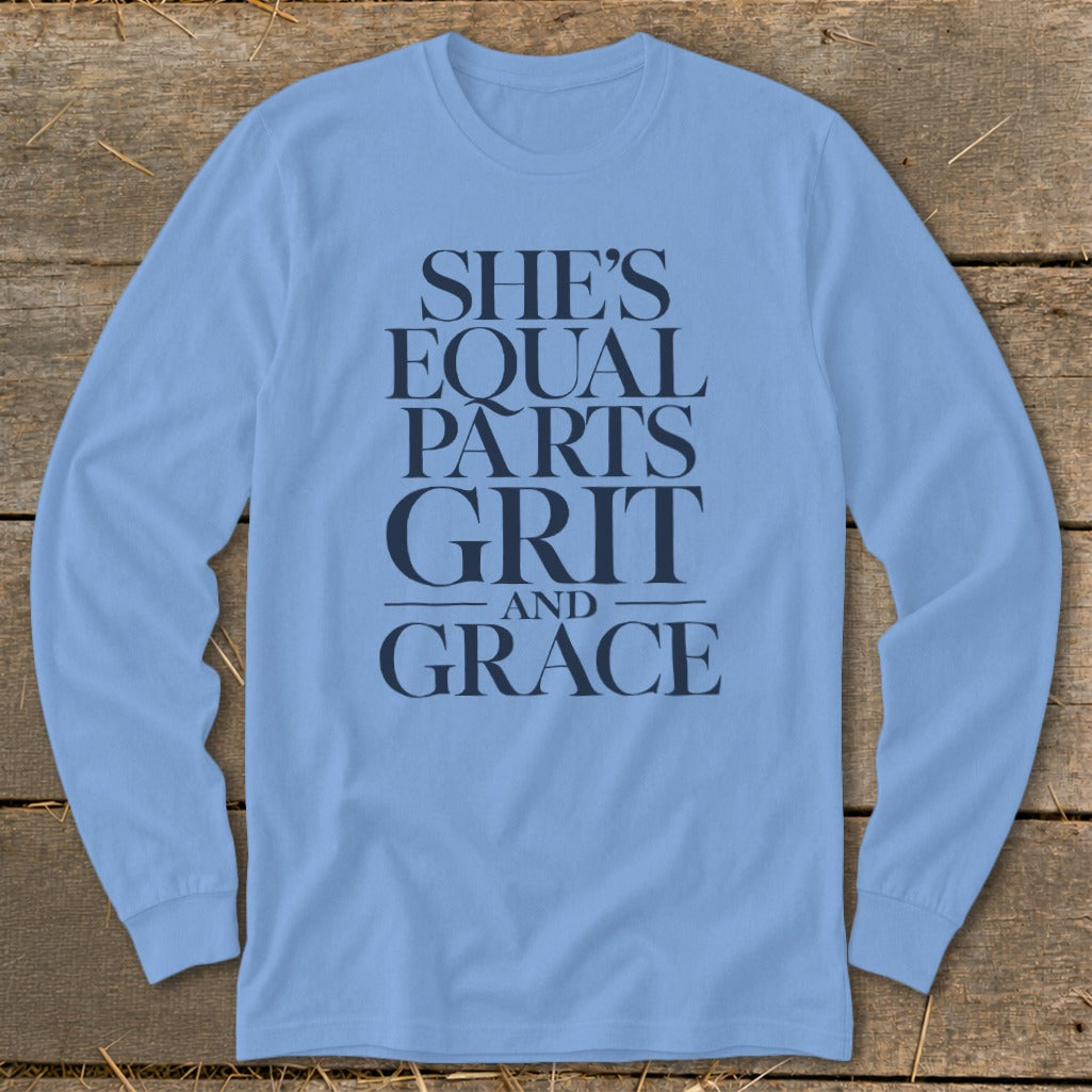 A light blue long-sleeved t-shirt featuring the navy text She's Equal Parts Grit and Grace.