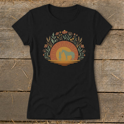 Black t-shirt with a sunset design featuring a person and horse surrounded by flowers.