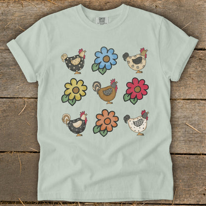 Light mint green t-shirt with a grid of six colorful chickens and six flowers.
