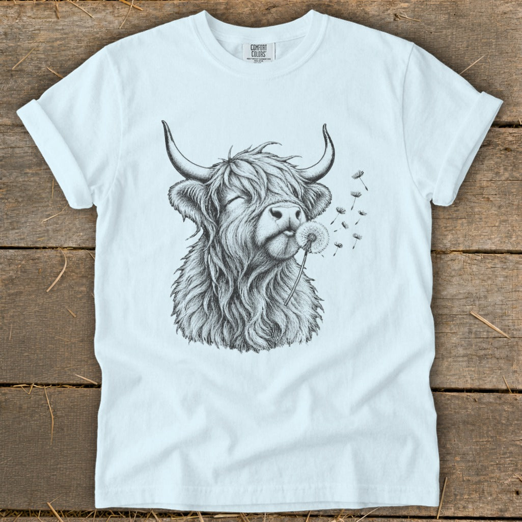 White t-shirt with sketch of a Highland cow blowing a dandelion.