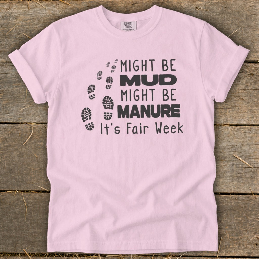 Pink t-shirt with black text and footprints that reads "Might be mud, might be manure, it's Fair Week."