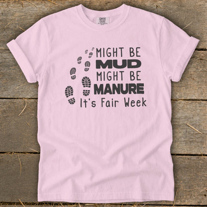 Pink t-shirt with black text and footprints that reads "Might be mud, might be manure, it's Fair Week."