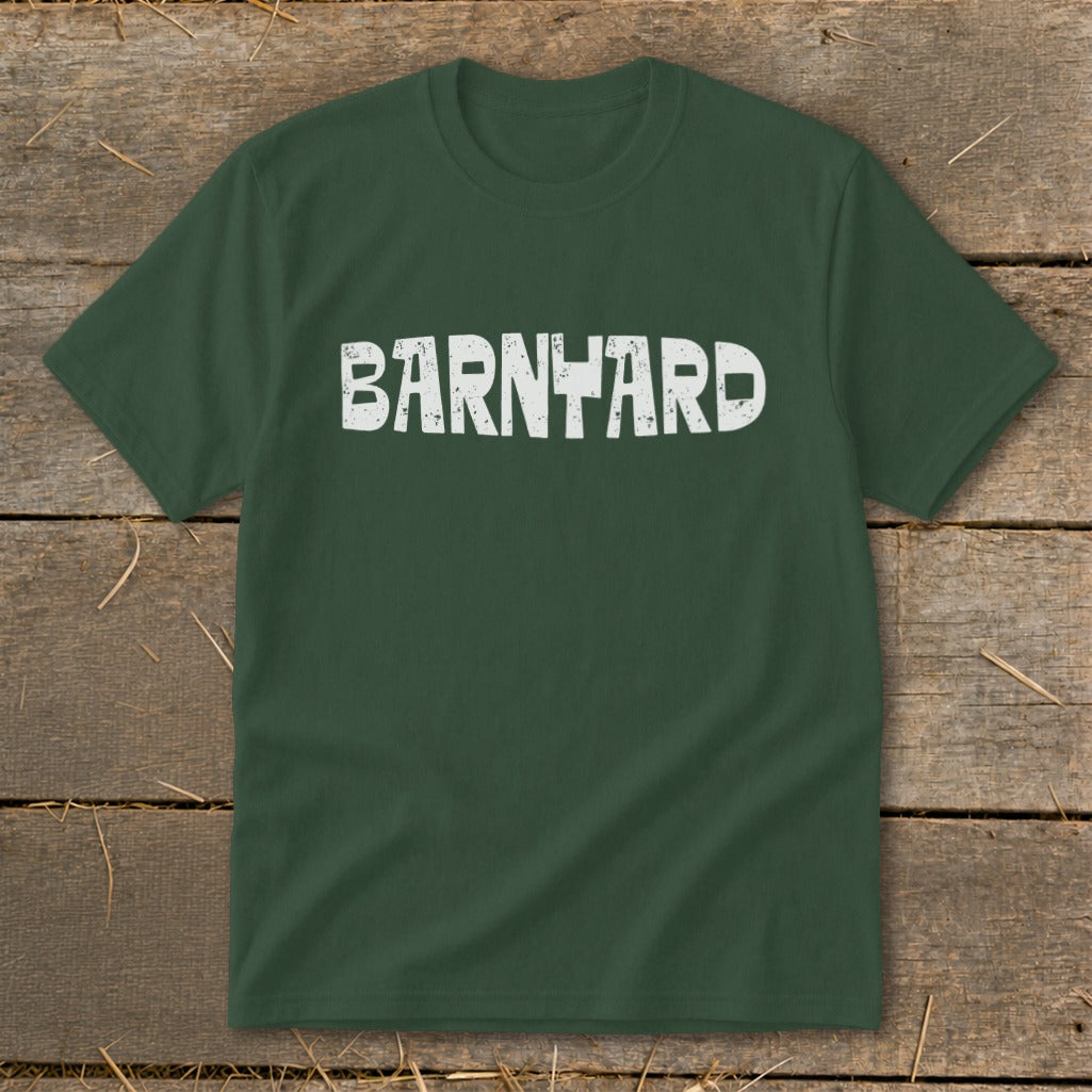 Dark green crewneck t-shirt featuring the distressed white text "BARNYARD" centered on the chest, laid flat on rustic wood.