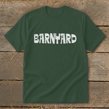 Dark green crewneck t-shirt featuring the distressed white text "BARNYARD" centered on the chest, laid flat on rustic wood.