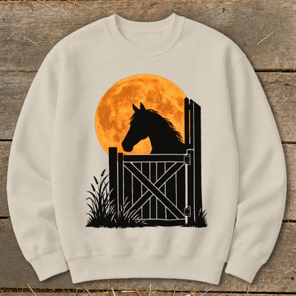 A cream-colored crewneck sweatshirt featuring a graphic of a horse silhouetted against a large orange moon.