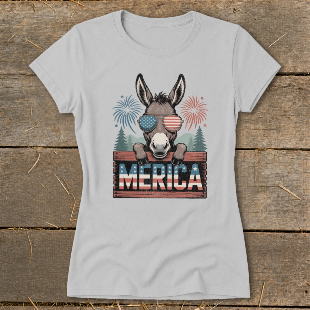 Donkey wearing American flag sunglasses peeking over "MERICA" sign with fireworks.