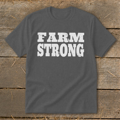 Dark gray crewneck t-shirt with distressed white text reading FARM STRONG centered on the chest, laid flat on wooden planks.