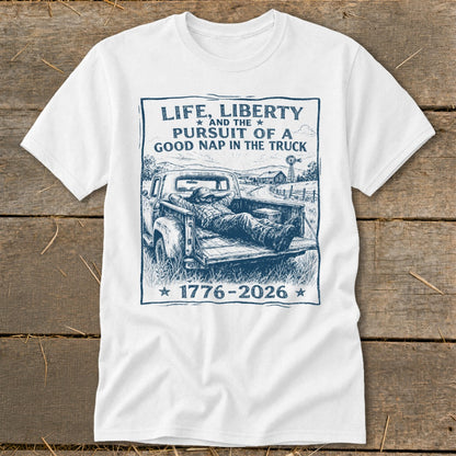 White t-shirt with blue graphic of man napping in truck bed, quote: Life, Liberty, Pursuit of a Good Nap.