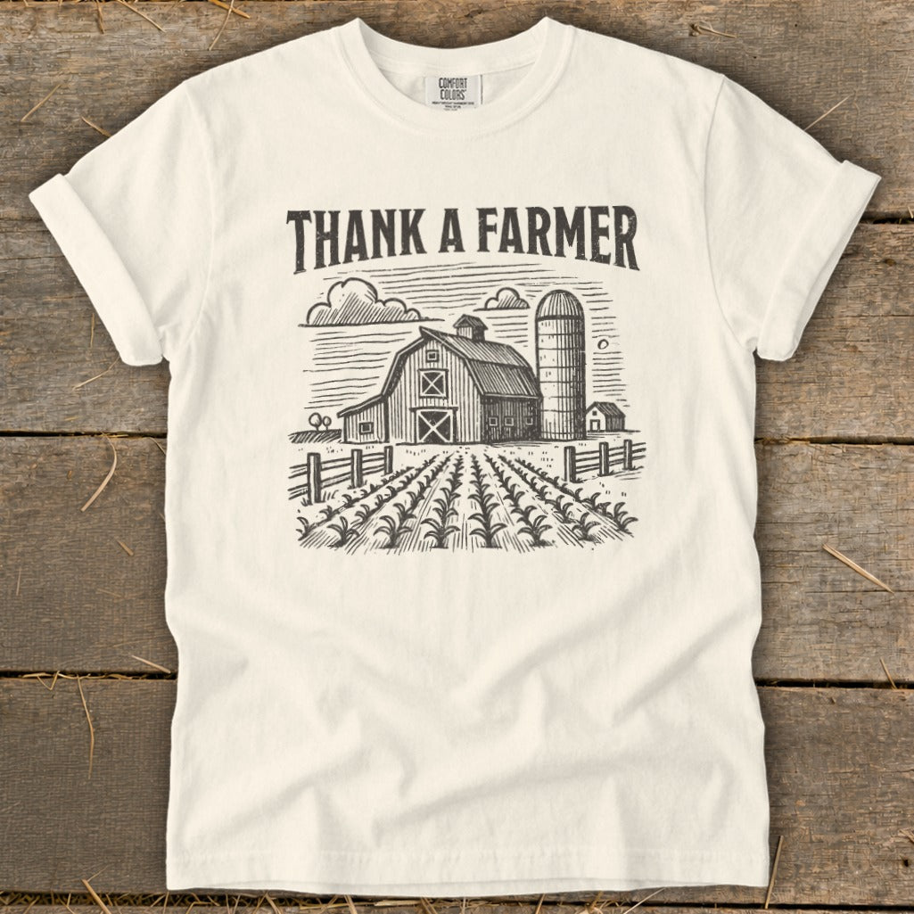 White t-shirt with "THANK A FARMER" and a barn, silo, and crops graphic.