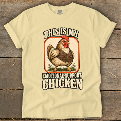 Light yellow t-shirt with a chicken wearing a vest and text "This is my emotional support chicken".